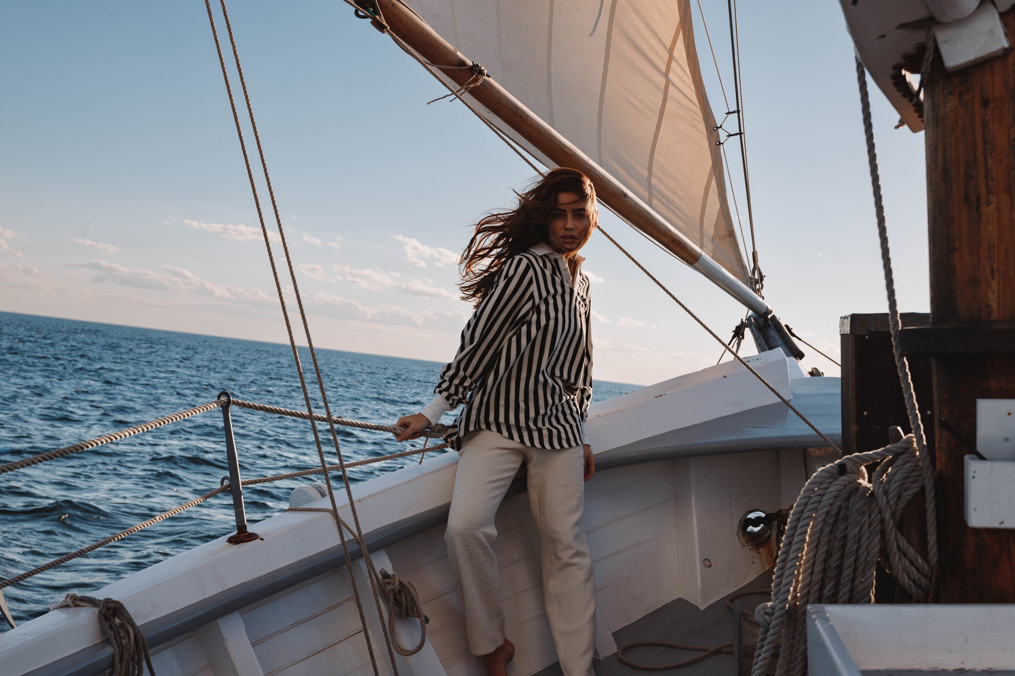 woman on sailboat in striped black and cream pullover sweater with cotton tweed cream pants