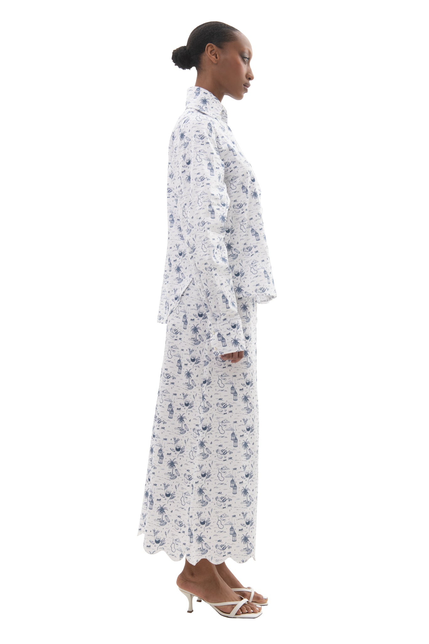 woman in matching toile print set in blue and white wearing a skirt with scalloped hem and shirt with notched hem
